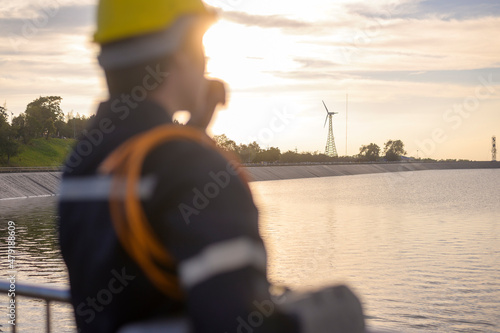 Fotografi A male engineer wearing a protective helmet at sunset , selective focus on backg