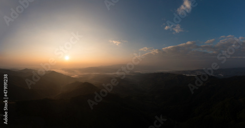 Mountain fog in the valley silhouette and morning sunlight blue sky background aerial view from drone in winter