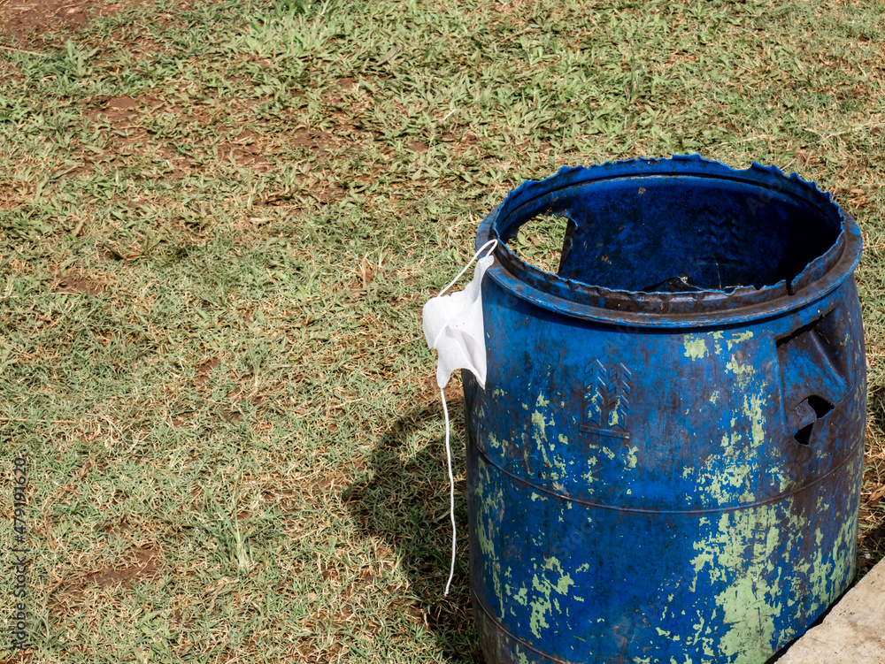 a white medical mask hanging on a blue trash can
a white medical mask hanging on a blue trash can
