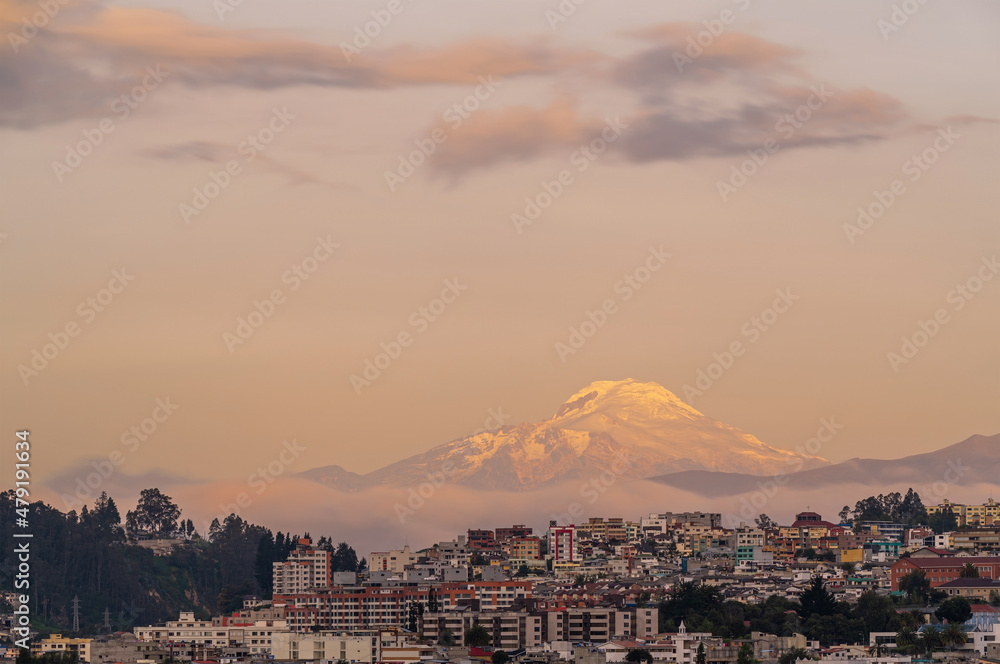 Quito cityscape at sunset with snowcapped Cayambe volcano, Andes mountains, Ecuador.