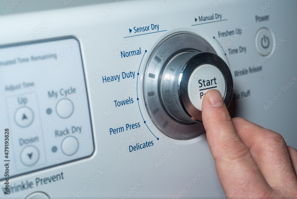 Finger pushing start button on electric dryer Finger pushing start button on electric dryer