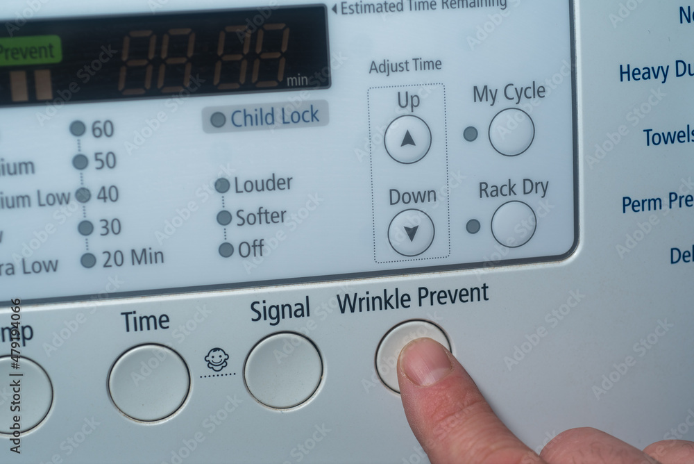 Finger pushing wrinkle prevent button on electric dryer Finger pushing wrinkle prevent button on electric dryer