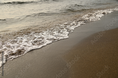 砂浜に打ち寄せる穏やかな波と白い泡