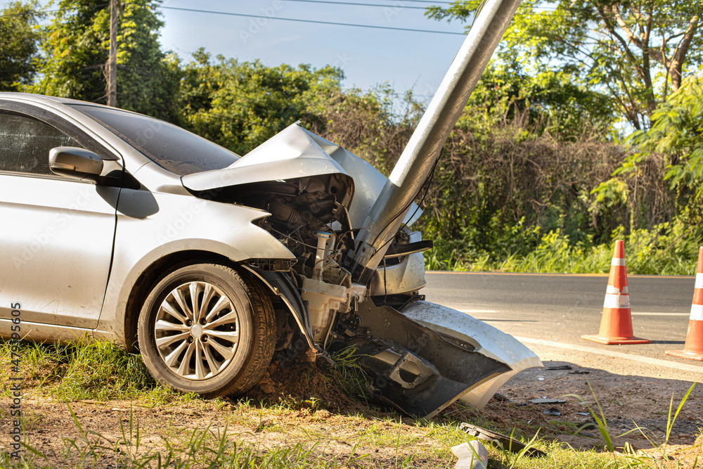 The white sedan was involved in a collision with an electric pole. - obrazy, fototapety, plakaty 