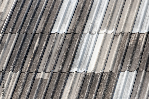 Old double corrugated roofing covered with dry moss and rust, White grey gypsum tile with stain on surface, Shingles texture, Abstract geometric pattern background, Details of roof top material.