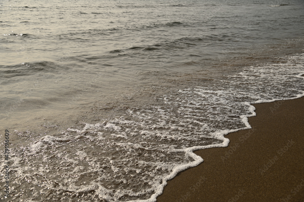 砂浜に打ち寄せる穏やかな波と白い泡