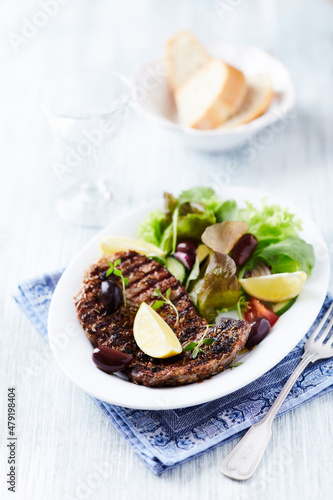 Grilled pork steak with fresh salad. Bright wooden background.