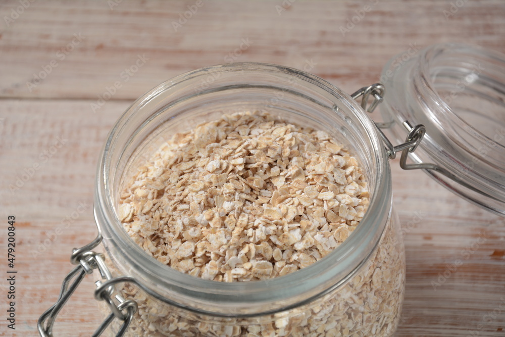 Uncooked oatmeal in a bowl on the table. Dehusked, hulled oats, rolled into large whole flakes. Porridge oats, used in granola or muesli. Uncooked oatmeal in a bowl on the table. Dehusked, hulled oats, rolled into large whole flakes. Porridge oats, used in granola or muesli.