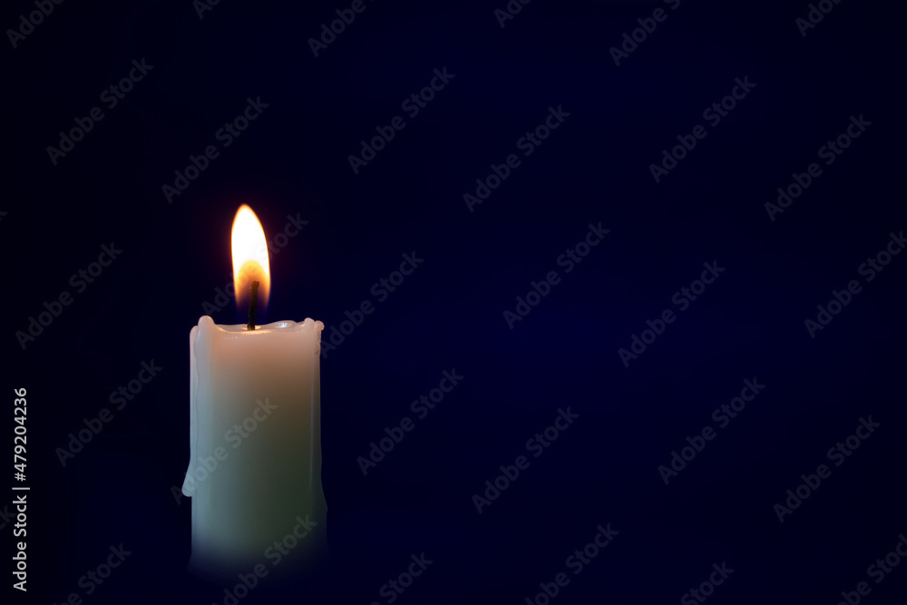 Burning candle on a dark blue background. Religious rites, in memory of the dead or holiday rites. Burning candle on a dark blue background. Religious rites, in memory of the dead or holiday rites.
