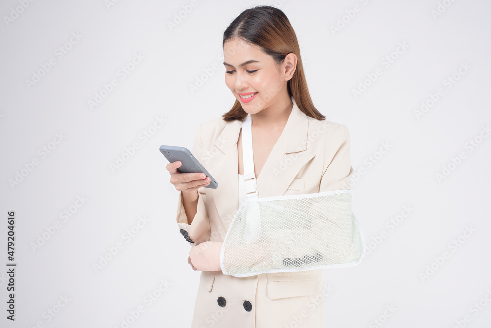 Portrait of young woman with an injured arm in a sling over white background in studio.. Portrait of young woman with an injured arm in a sling over white background in studio..