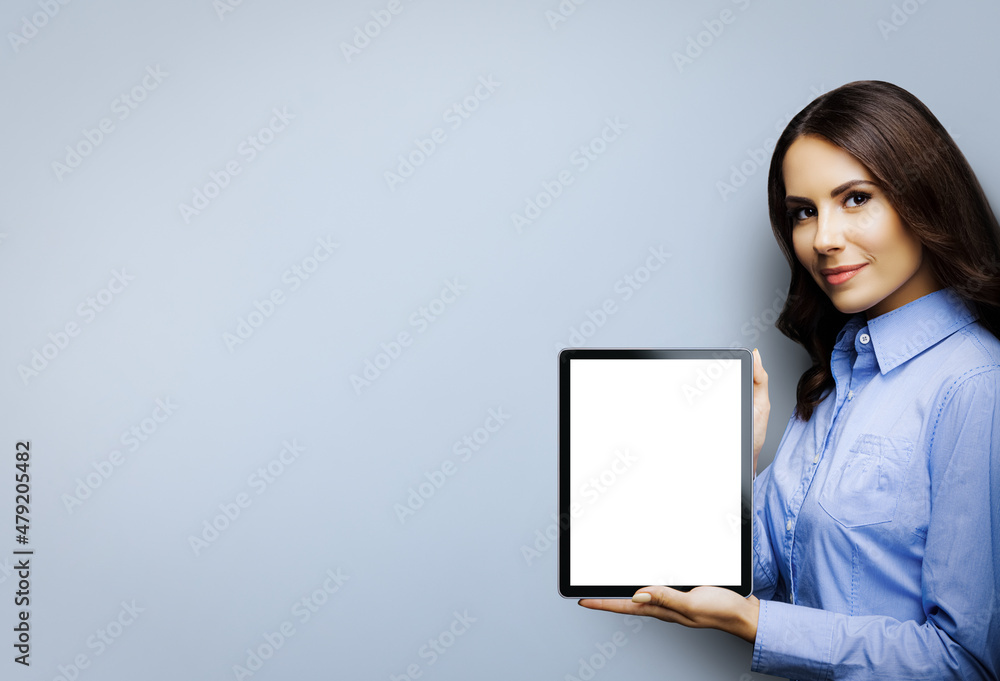 Portrait of smiling brunette businesswoman showing tablet pc, touchpad, with copy space for text, isolated over grey color background. Confident beautiful business woman at studio Portrait of smiling brunette businesswoman showing tablet pc, touchpad, with copy space for text, isolated over grey color background. Confident beautiful business woman at studio