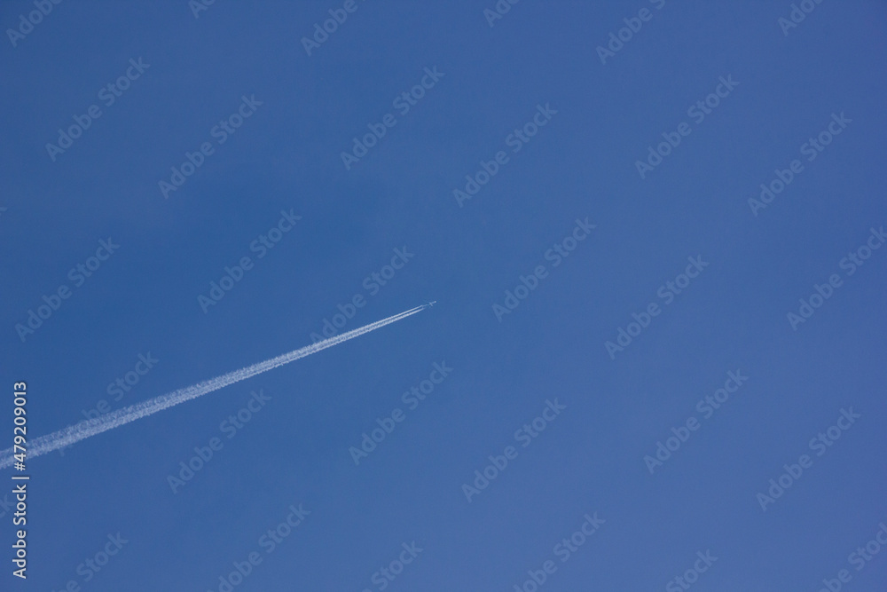 Airplane with white tail flying over blue sky in sunshine Airplane with white tail flying over blue sky in sunshine