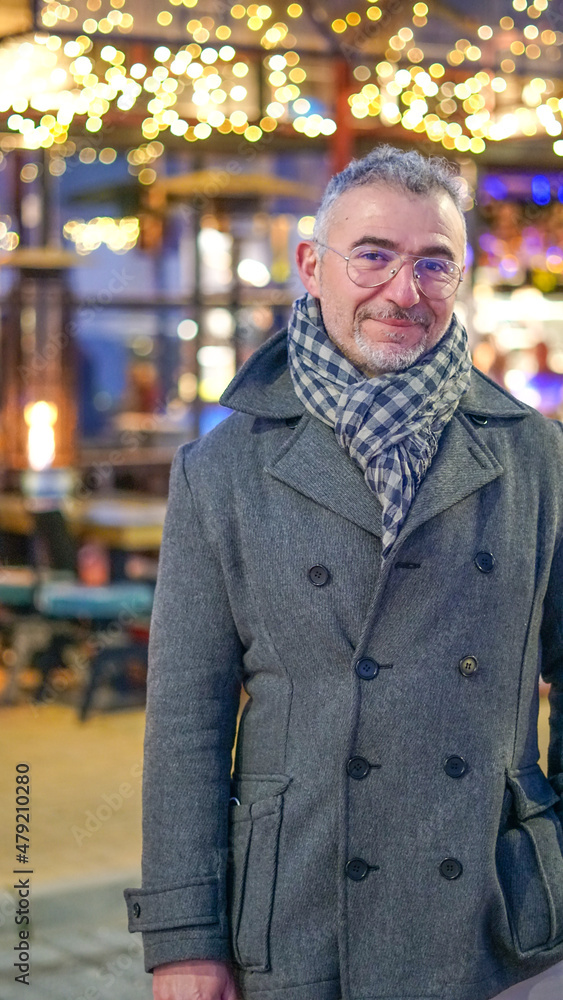 Hombre de mediana edad con abrigo y bufanda con boké de fondo de luces amarillos Hombre de mediana edad con abrigo y bufanda con boké de fondo de luces amarillos
