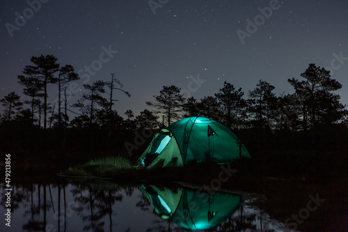 Green tent in the forest with light at night