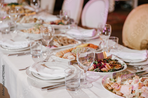 Table setting for a banquet or celebration.Empty glasses for alcoholic beverages  wine and juice  a set table.Cloth napkins on a white platter and cutlery on the table.Cold appetizers and salads