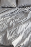gray linens in sunlight on  bed in  bedroom