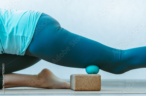 Close up of person doing quadriceps muscle fascia release with therapy massage ball on cork block. Concept: self care practices at home, pre-sport MFR, fascia hydration photo