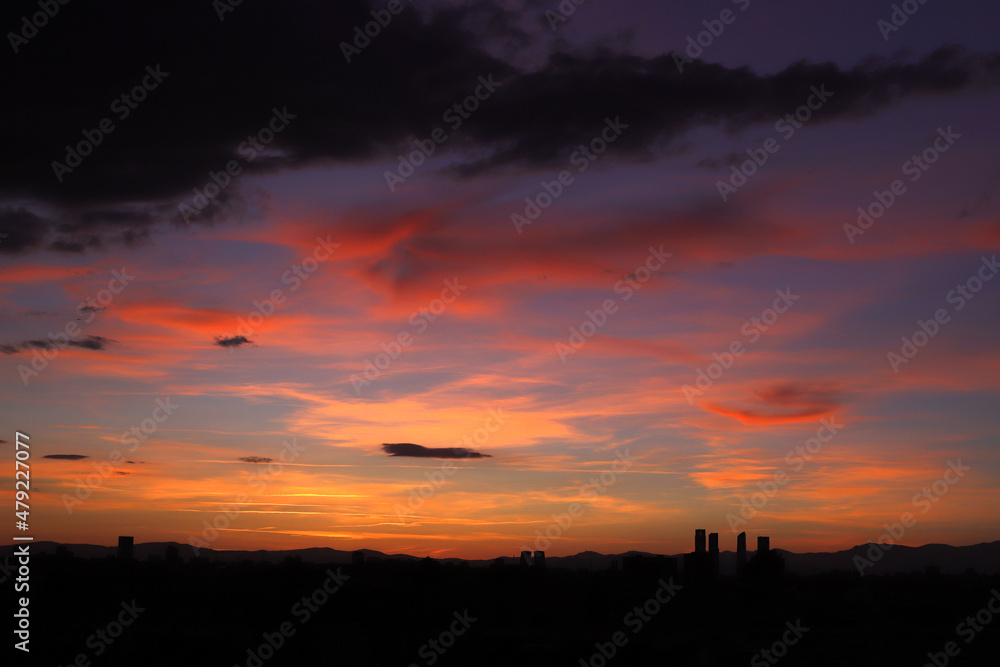 paisaje de Madrid en puesta de sol con nubes de colores rojizos