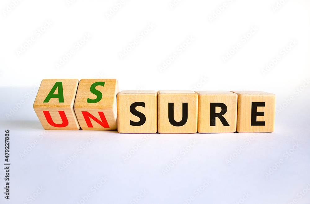Assure or unsure symbol. Turned wooden cubes and changed the concept word unsure to assure. Beautiful white table, white background, copy space. Business and assure or unsure concept. Assure or unsure symbol. Turned wooden cubes and changed the concept word unsure to assure. Beautiful white table, white background, copy space. Business and assure or unsure concept.