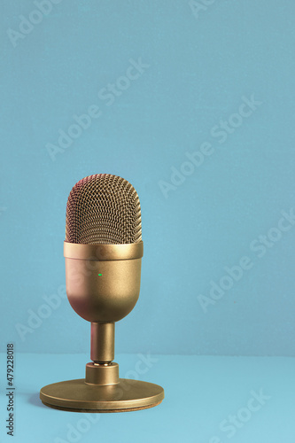 Elegant and luxuriously designed gold microphone for recording on a pastel-colored textured background with copy space. Contests and entertainment.