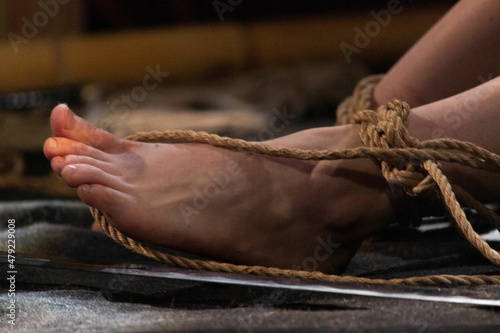 tied legs of a girl on stage during a performance at a bdsm festival. reportage shooting.