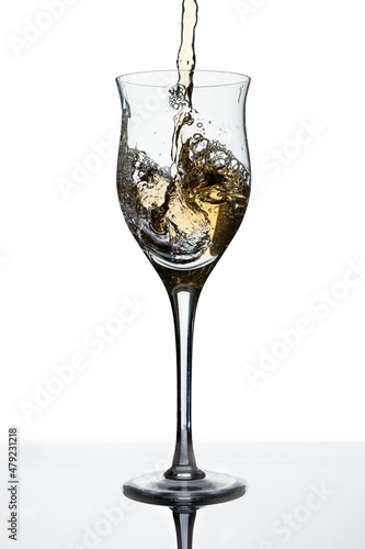 Serving a slightly tilted glass with white wine. White background. Copy space. Concept of movement, elegance, taste.