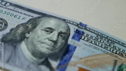 Macro video shooting. Close-up of a hundred dollar bill sliding across the table. $ 100 appears in the frame and then disappears. George Washington on the US banknote. Money and finance, cash. photo