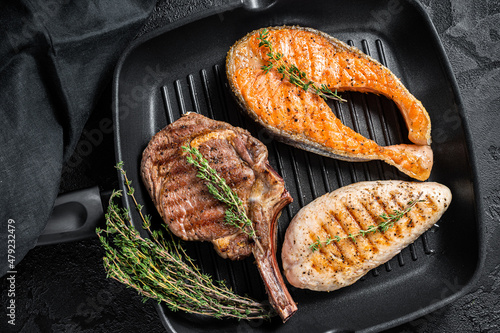 Grilled steaks. Beef rib eye, salmon and Turkey breast. Organic fish, poultry and beef meat. Black background. Top view