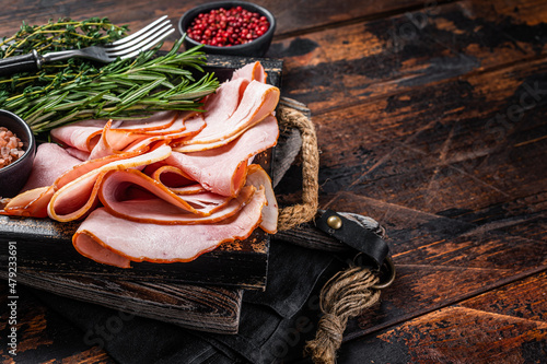Italian Prosciutto cotto Ham slices in wooden tray with thyme and rosemary. Wooden background. Top view. Copy space photo