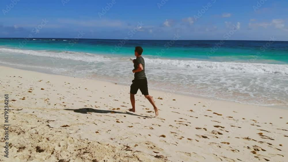 Running man outdoors beach run. Young attractive man barefoot doing sport exercises in the morning on sunrise beach by sea, jogging, healthy lifestyle, active life, smiling, happy, work out. Jogging.