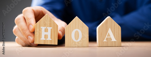 Hand Placing Wooden House HOA Blocks Over photo