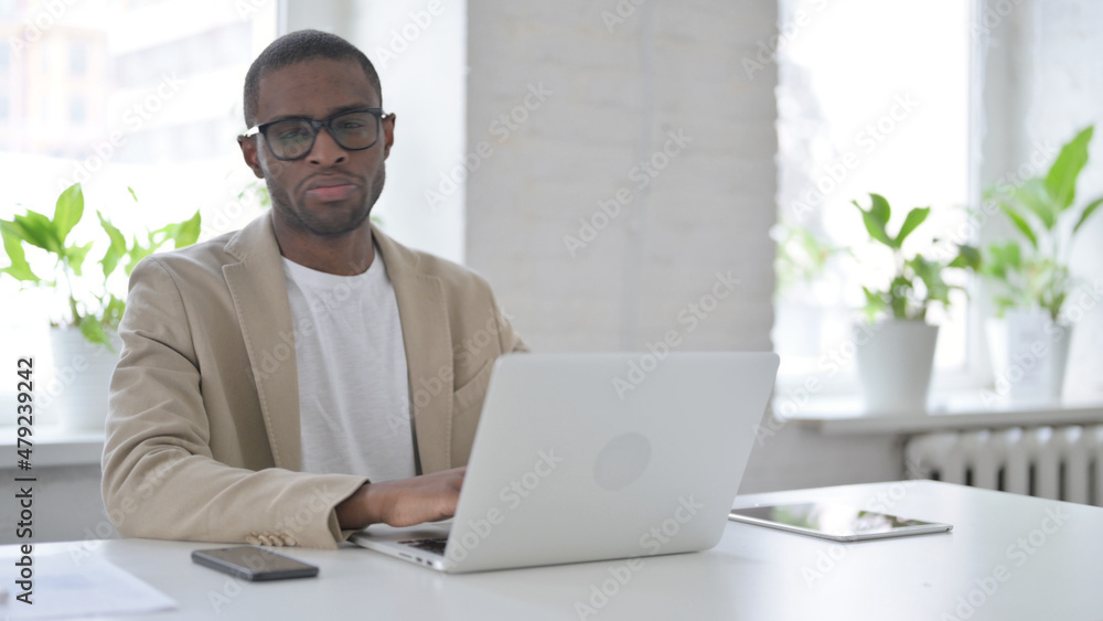 African Man Shaking Head as No Sign while using Laptop in Office African Man Shaking Head as No Sign while using Laptop in Office