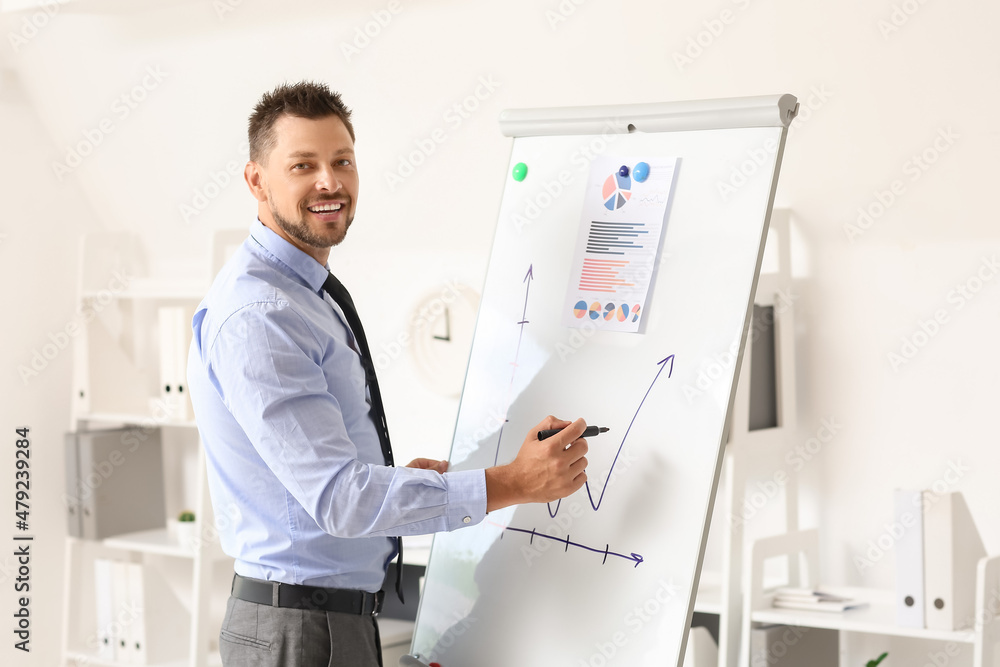 Handsome businessman writing on flipchart in office