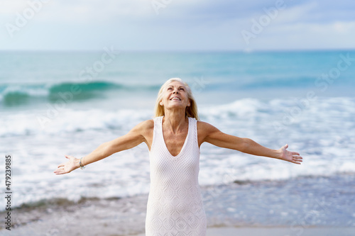 Mature woman opening her arms on the beach, spending her leisure time, enjoying her free time #479239885
