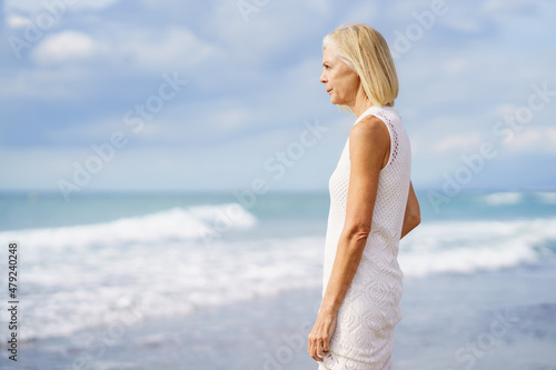 Mature woman gazing serenely at the sea. Elderly female standing at a seaside location © javiindy