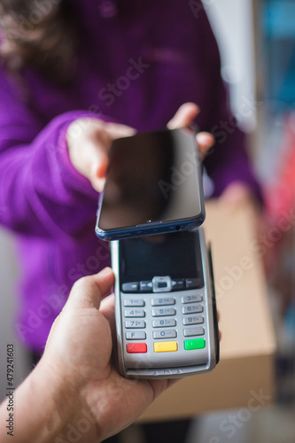 Smiling woman doing contactless payment while receiving package photo