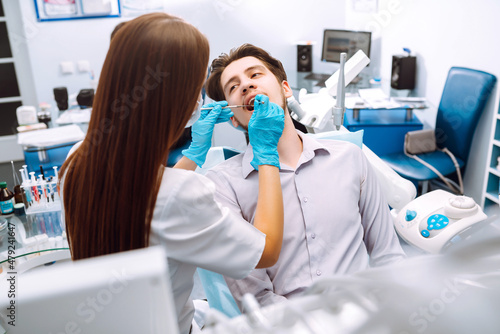 Young man at the dentist s chair during a dental procedure. Overview of dental caries prevention. Healthy teeth and medicine concept.