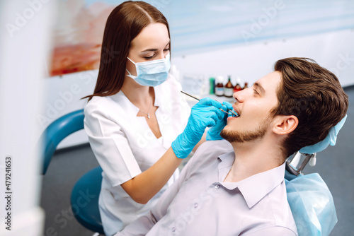 Young man at the dentist's chair during a dental procedure. Overview of dental caries prevention. Healthy teeth and medicine concept.