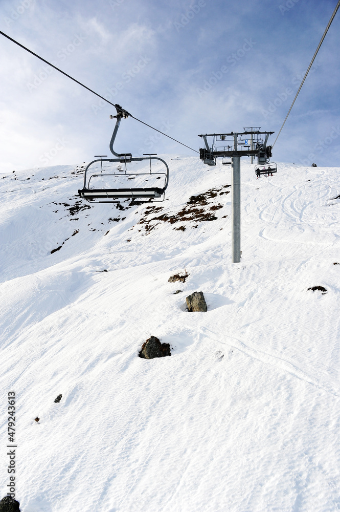 Empty chair lift over snowy ski slopes in French alps 