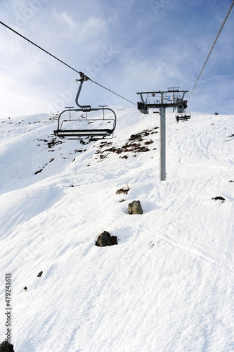 Empty chair lift over snowy ski slopes in French alps 