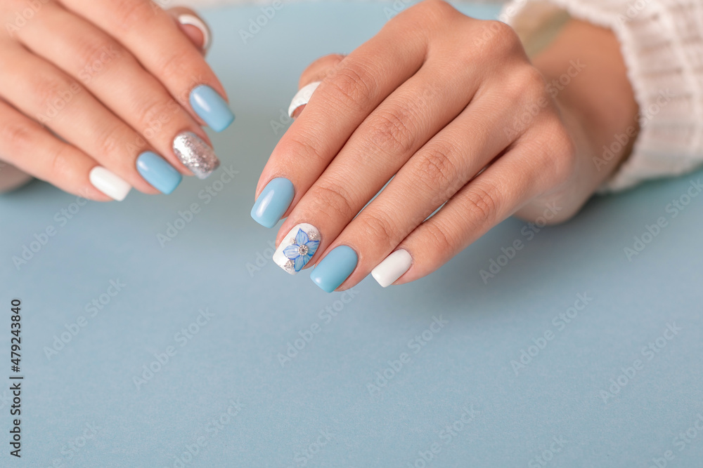 Fototapeta premium Beautiful female hands with romantic manicure nails, blue and white gel polish