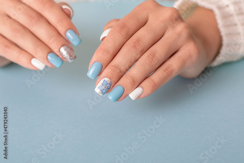 Beautiful female hands with romantic manicure nails  blue and white gel polish