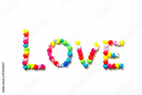 The word "love" is made of colorful hearts of beads. The concept of Valentine's Day. Beads in the form of hearts. Flat layout, top view