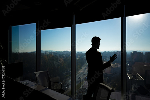 Silhouette of a businessman man in a modern office on the background of the window, a man talking on the phone