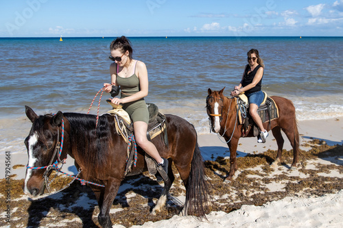 Mother and teenage daughter horseback riding on tropical island beach of Cozumel, Mexico photo