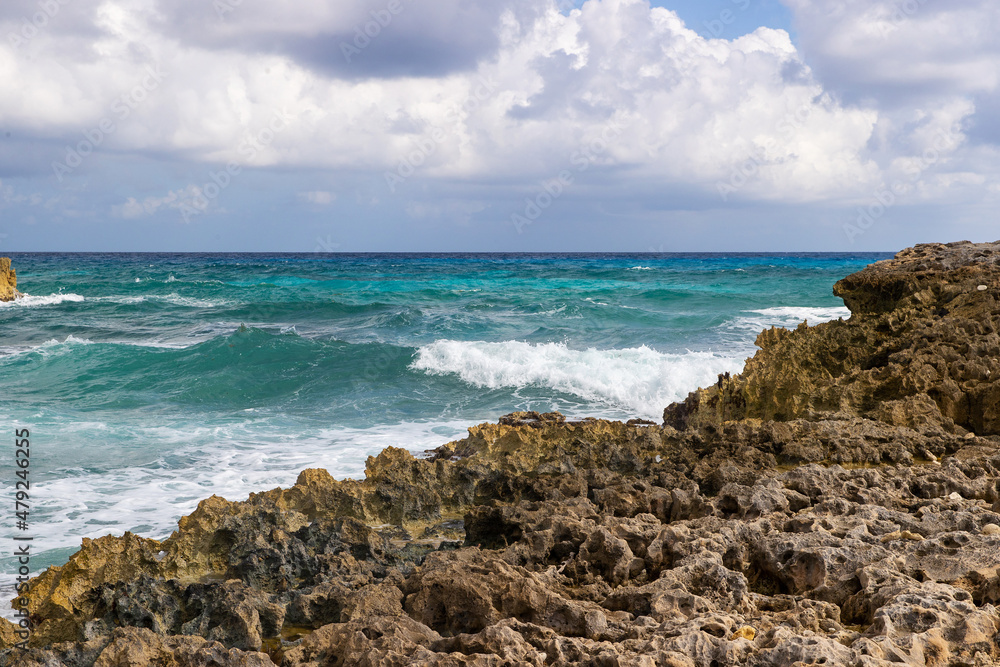 Vibrant turquoise blue ocean water with waves crashing on the limestone rocky shore of Cozumel, Mexico Vibrant turquoise blue ocean water with waves crashing on the limestone rocky shore of Cozumel, Mexico