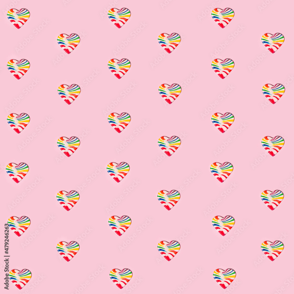 Pattern made of heart shaped candies. Colorful lollipops on pastel light pink background. Creative Valentine's day flat lay concept.