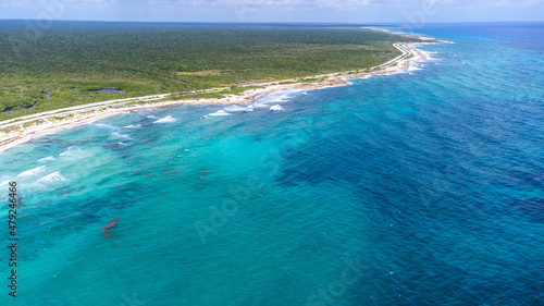 Lush jungle and beautiful turquoise Caribbean ocean water on the beach of Cozumel captured by a drone flying over Quintana Roo, Mexico.  photo