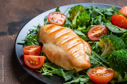 Grilled chicken breast, chicken fillet and fresh vegetable salad closeup on wooden table. Healthy lunch menu. Healthy food, keto diet, dieting concept