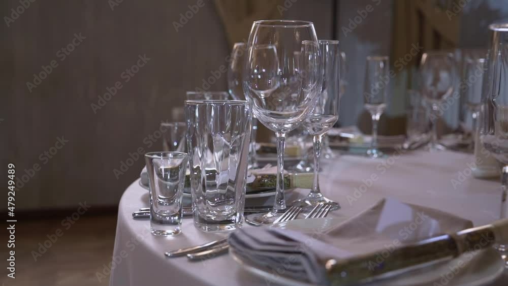 Served table in a restaurant for dinner, lunch or celebration. White tablecloth, plates, napkins and glasses. Holiday indoors. Empty with no people and food. Decorated for wedding. Served table in a restaurant for dinner, lunch or celebration. White tablecloth, plates, napkins and glasses. Holiday indoors. Empty with no people and food. Decorated for wedding.